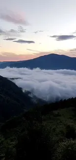 Misty mountains at sunrise with clouds in a tranquil scene.