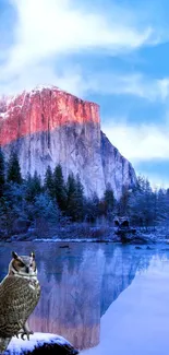 Owl perches by lake with snowcapped mountain view.