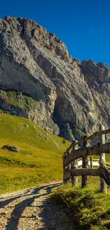 Serene mountain path under a blue sky with towering rocks and green hills.