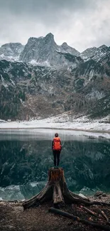 Person on a stump overlooking a mountain lake.