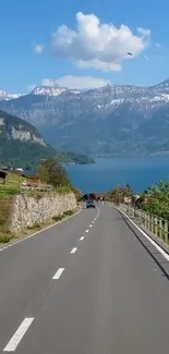 Scenic mountain road with lake and clear blue sky mobile wallpaper.