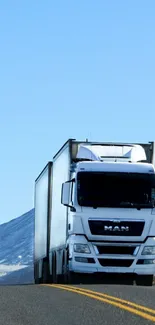 White semi-truck on mountain road under blue sky wallpaper.