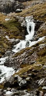 Serene mountain stream with cascade waterfalls in rugged terrain.