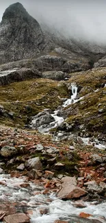 Mountain stream cascading through rocky, misty landscape.