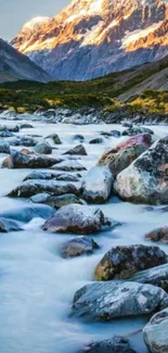 Scenic view of mountain stream at sunset with glowing peaks.