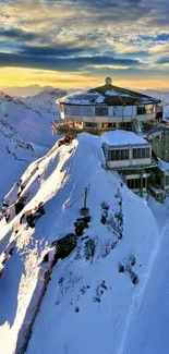 Chalet perched on snowy mountain at sunrise with vibrant sky.