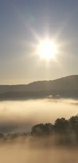 Mountain sunrise with mist and sun rays illuminating the scenic landscape.