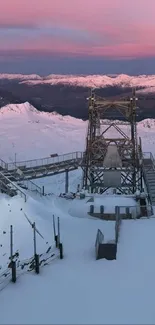 Snowy mountain landscape at sunset with pink skies.