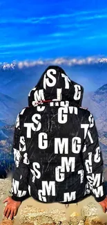 Hooded person with letters overlooking mountain landscape.