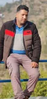 Man sitting on a bench with mountains in the background.