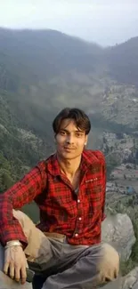 Person in red plaid shirt with mountain backdrop.