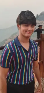 Person in colorful striped shirt with mountain backdrop.