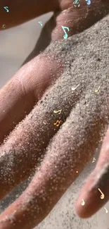 Hand covered in sand with floating music notes.