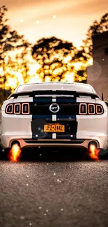 White Mustang car with flaming exhaust at sunset.