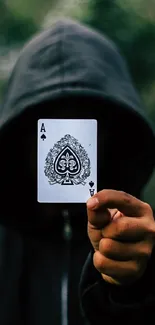 Hooded figure holding an ace card in a mysterious forest scene.