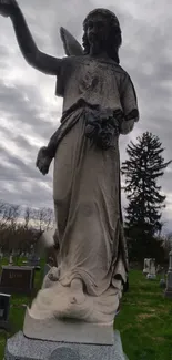 Serene statue in a cloudy cemetery scene.