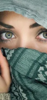 Captivating green eyes hidden behind a patterned grayish-green scarf.