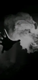 Mysterious hand reaching through smoke in dark wallpaper.