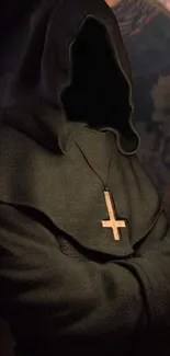 Hooded figure in dark robe with cross necklace, mysterious atmosphere.