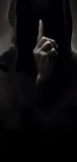 Mysterious hooded figure with finger raised in a dark setting.