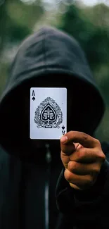 Hooded figure holding ace of spades card