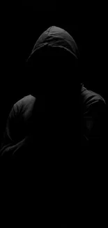 Mysterious shadowy figure in a hoodie on a dark background.