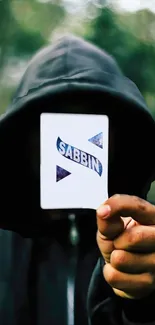 Mysterious hooded figure holding a card in a dark forest.