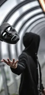 Hooded figure tossing a black mask in an arched walkway.