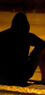 Silhouette of a person sitting on steps at night with amber street lighting.