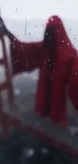 Blurred figure in red cloak with raindrops on glass.