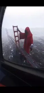 Red cloaked figure on bridge in foggy landscape.