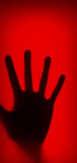 Silhouette of a hand against a vibrant red background.