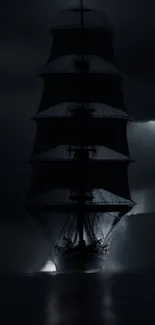 Silhouetted ship sailing under moonlight.