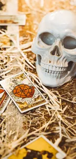 A skull surrounded by tarot cards and straw on a textured surface.