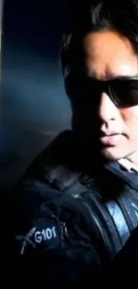 Mysterious man in leather jacket with sunglasses in low light.