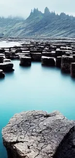 Scenic landscape with rocks and calm waters against a mountain backdrop.