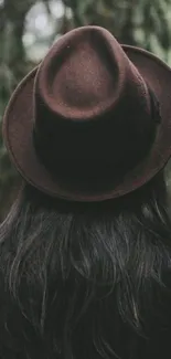 Person in brown hat in mysterious forest setting.