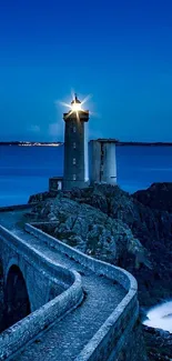 Lighthouse on rocky coast with deep blue sea at dusk.