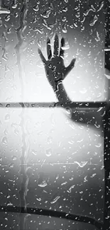 Shadowed hand behind rainy glass wallpaper with moody atmosphere.