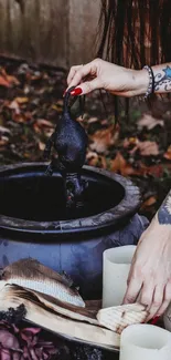 Mystical autumn ritual scene with cauldron and tattooed arms.