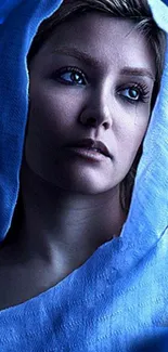 Serene portrait of a woman in blue hood under soft lighting.