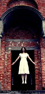 Woman in white dress at rustic brick structure.