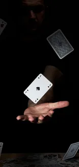 Magic trick with cards floating and a hand in the dark.