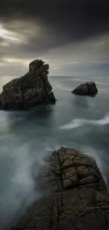 Coastal rock formation under dramatic sky in mobile wallpaper.