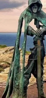 Mystical hooded statue on a coastal clifftop, overlooking the sea at sunset.