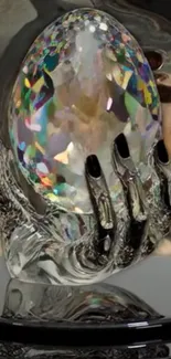 Mystical hand holds a vibrant crystal orb on a reflective surface.