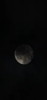 Moon against a dark, mystical black background on mobile wallpaper.