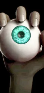 A hand holding a mystical eyeball against a dark background.