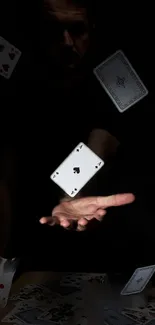 Floating playing cards in dim light, hand in action.