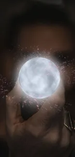 Hand holding a glowing mystical orb with sparkles.